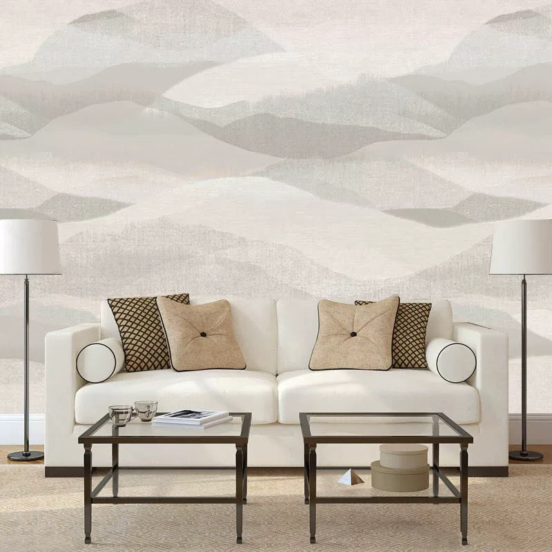 Modern living room with a white sofa, decorative pillows, and glass coffee tables against a textured wall mural.