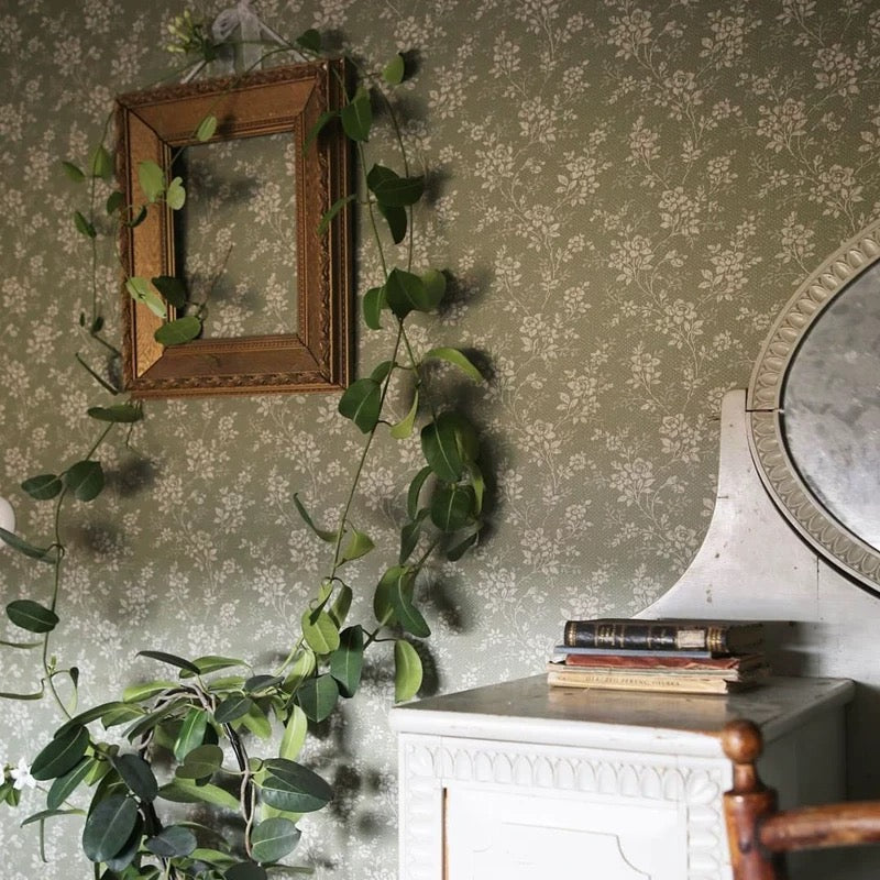 Decorative wall with floral wallpaper, wooden frame, and greenery