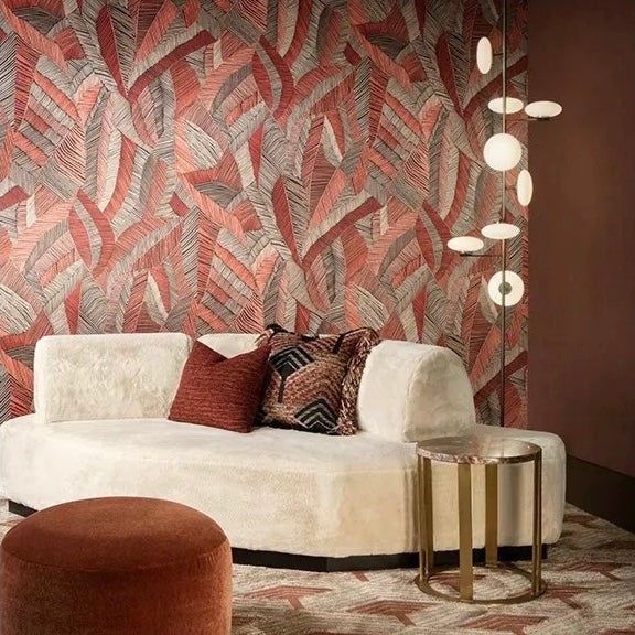 Modern living room with a white sofa, leaf patterned wall, and decorative pillows.