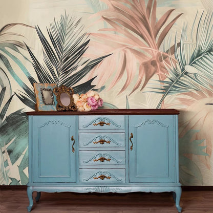 Blue cabinet with decorative elements against a tropical leaf wallpaper