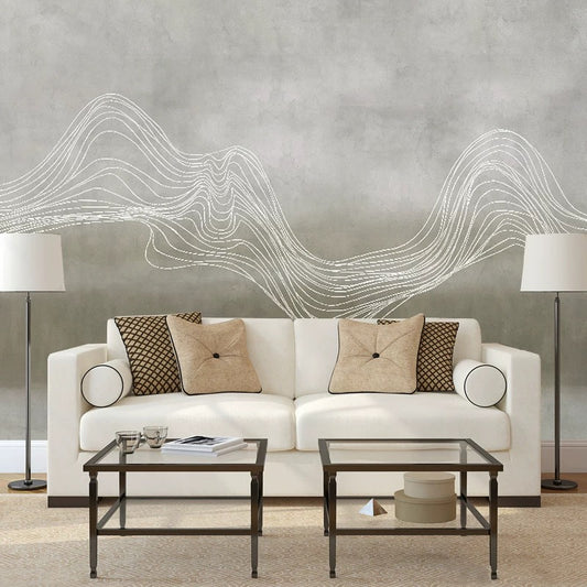 Modern living room with a white sofa, decorative pillows, and a abstract wall design.