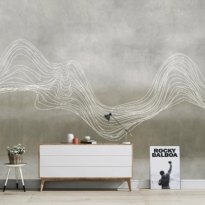 Modern interior with a white dresser, lamp, and a poster against a gray wall with wavy line art.