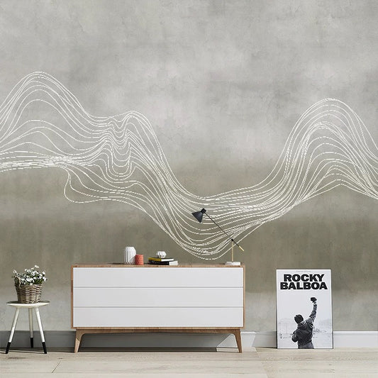 Modern interior with a white dresser, lamp, and a poster against a gray wall with wavy line art.