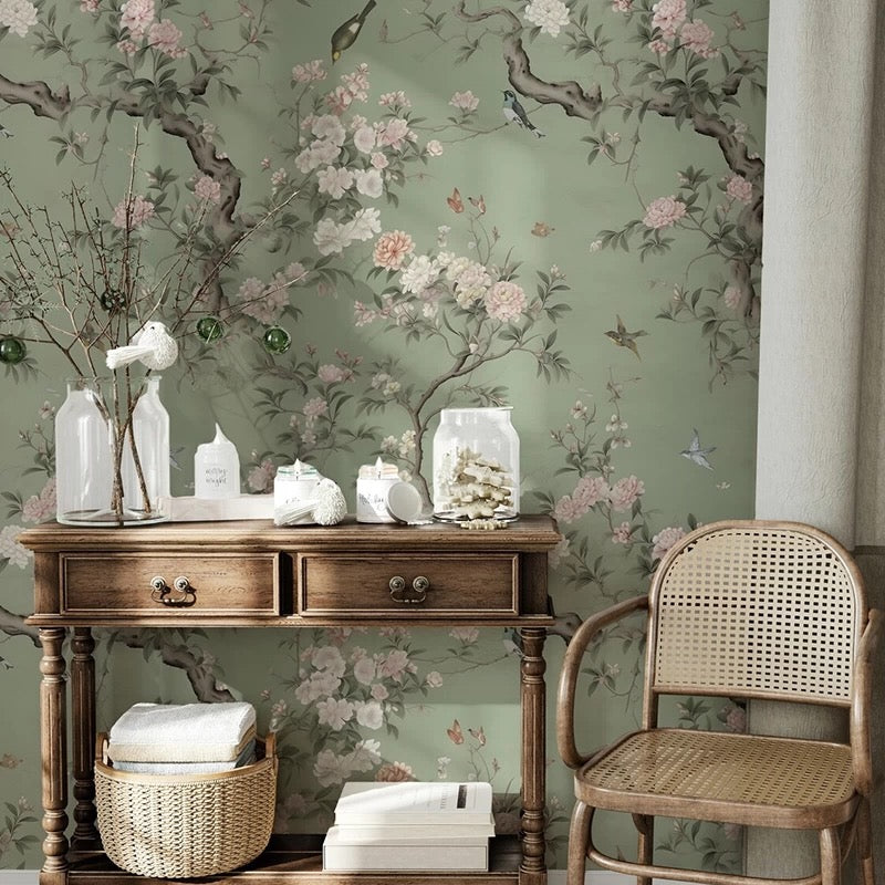 Decorative room interior with floral wallpaper mural, wooden console table, and wicker chair.