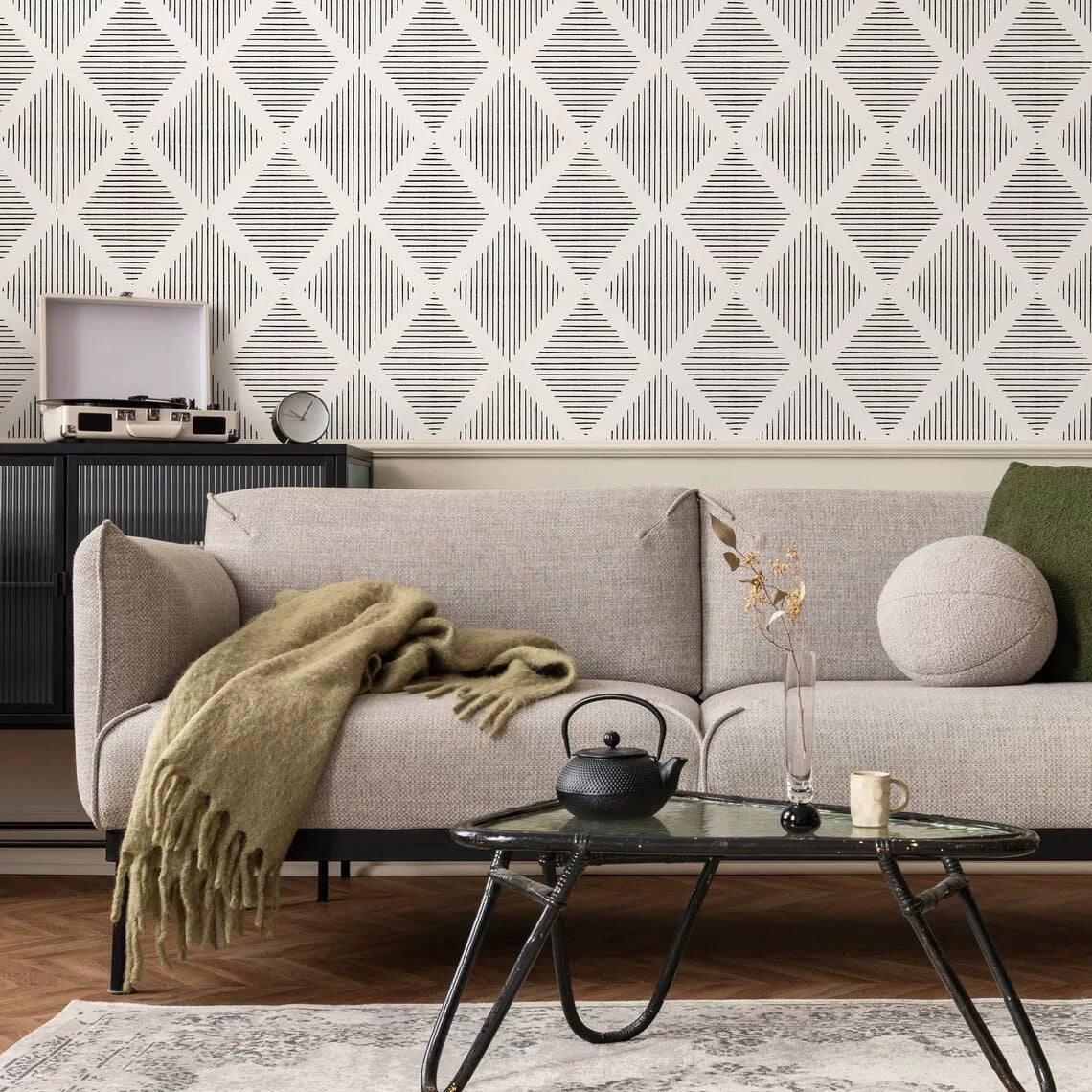 Living room with a gray sofa, green blanket, and decorative items against a geometric wallpaper.