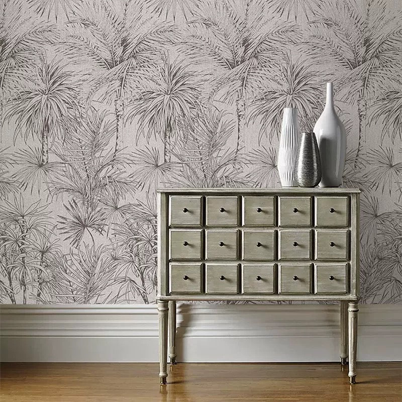 Wooden dresser with decorative vases against a wall mural with palm leaf pattern