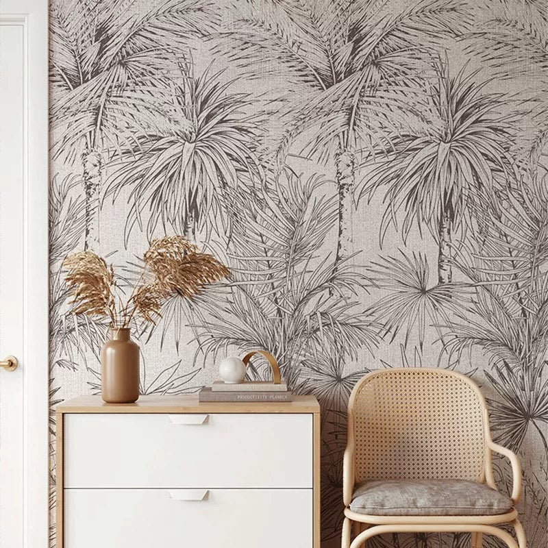Room interior with palm leaf wallpaper, white cabinet, and wicker chair.