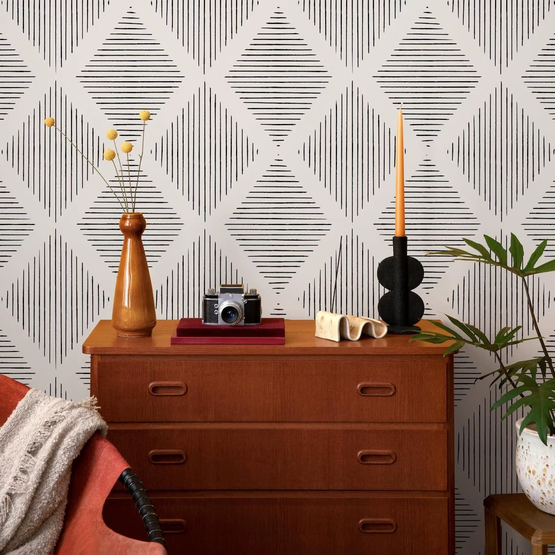 Wooden dresser with decorative items against a geometric patterned wall.