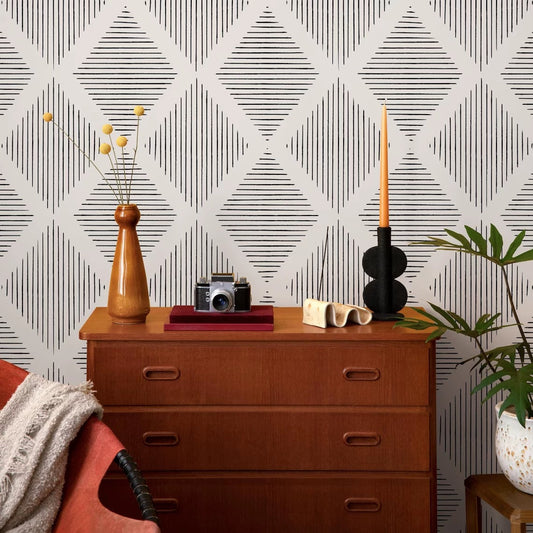 Wooden dresser with decorative items against a geometric patterned wall.