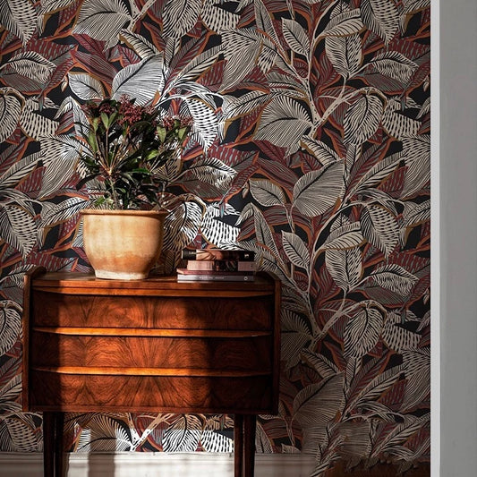Wooden side table with a plant against a leaf-patterned wall