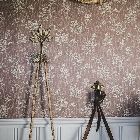 Decorative wall hook and a floral wallpapered wall.